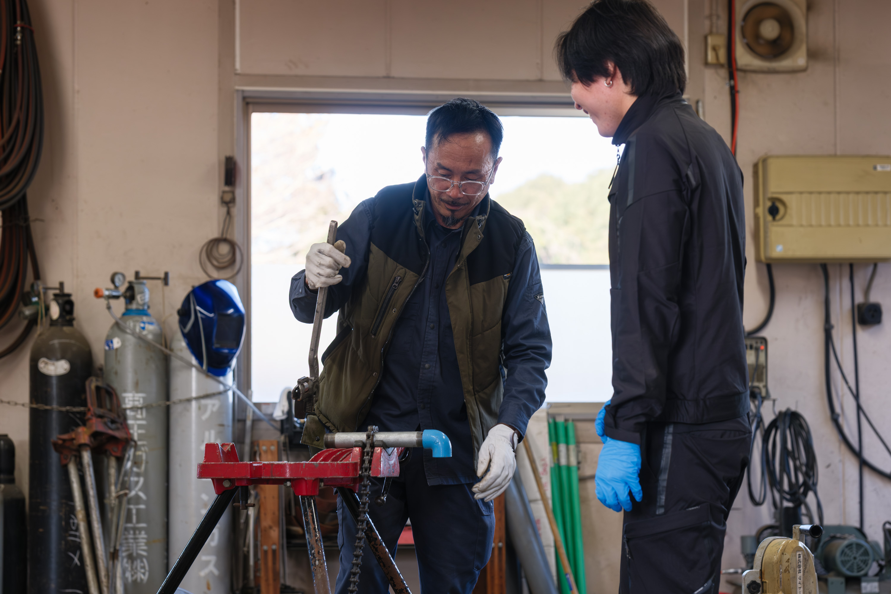 工場で先輩スタッフから配管加工を学ぶ若手社員